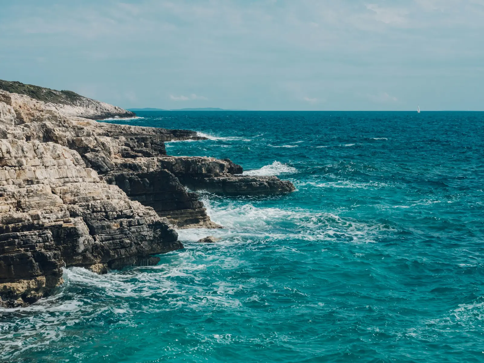 Layered limestone cliffs and deep blue sea at Duga Uvala on the eastern coast of Istria, Croatia