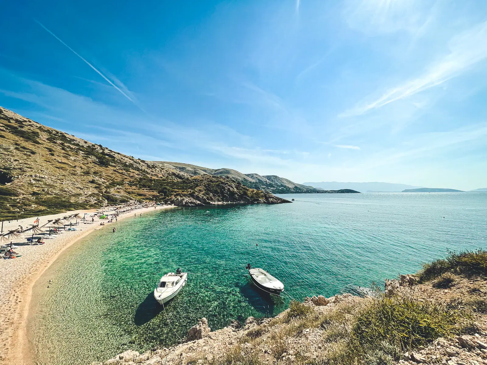 Turquoise pebble beach with small boats on the Croatian coast