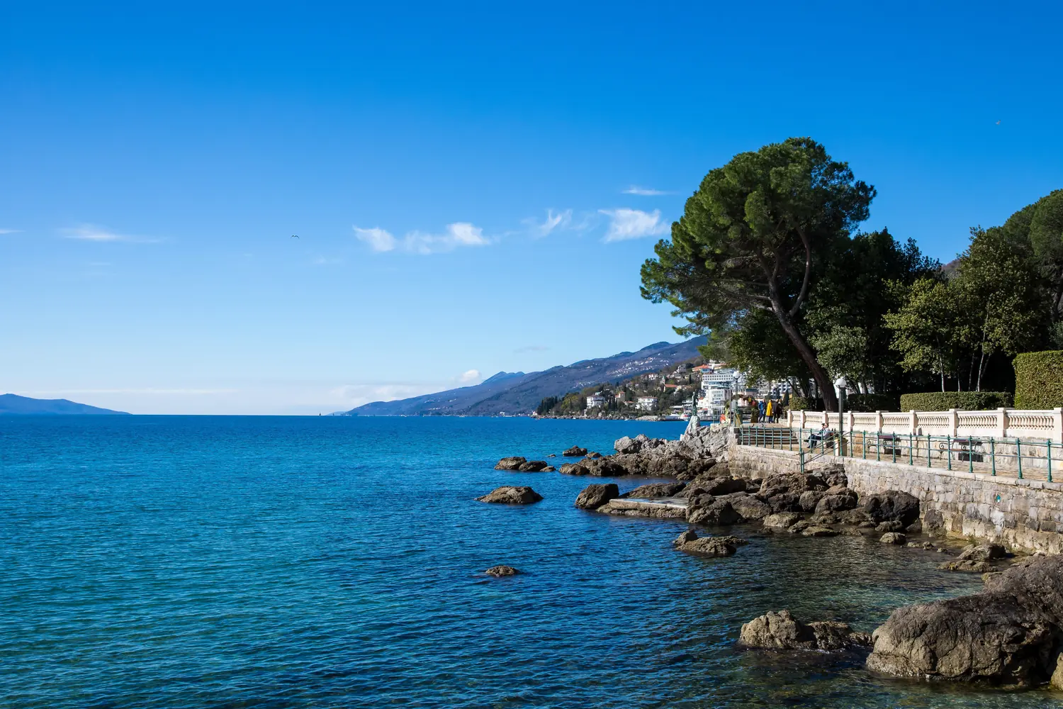 Rocky shoreline of the Opatija riviera with the Kvarner bay and mountains across the water, Croatia