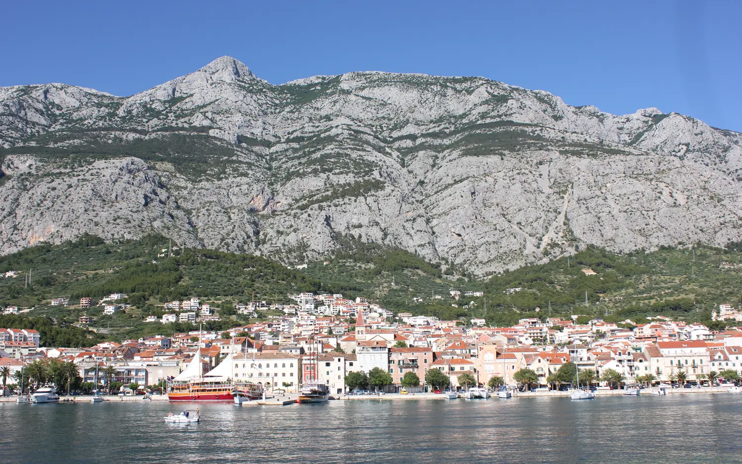 The waterfront of Makarska below the steep grey wall of the Biokovo mountain range, Central Dalmatia, Croatia