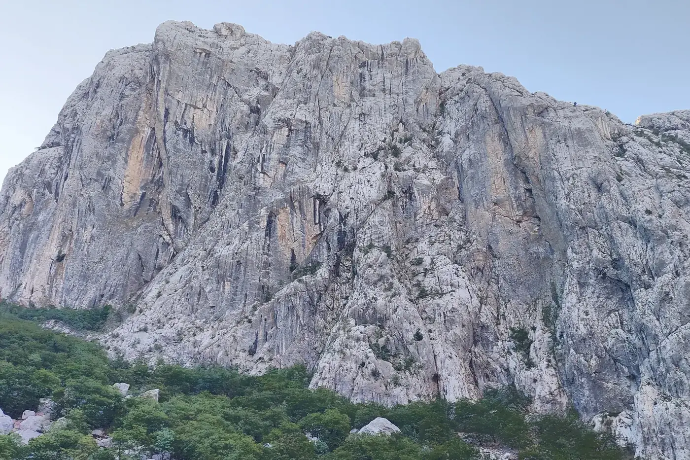 The vertical limestone wall of Anića kuk rising above forest in Paklenica National Park, Croatia
