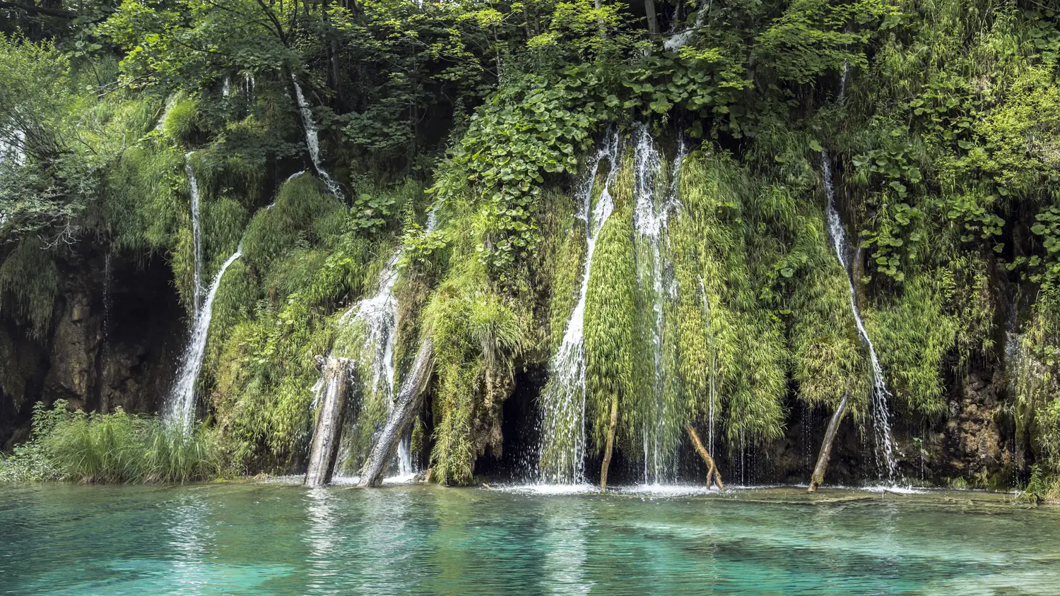 Waterfalls cascading into a turquoise lake in Plitvice Lakes National Park, Croatia