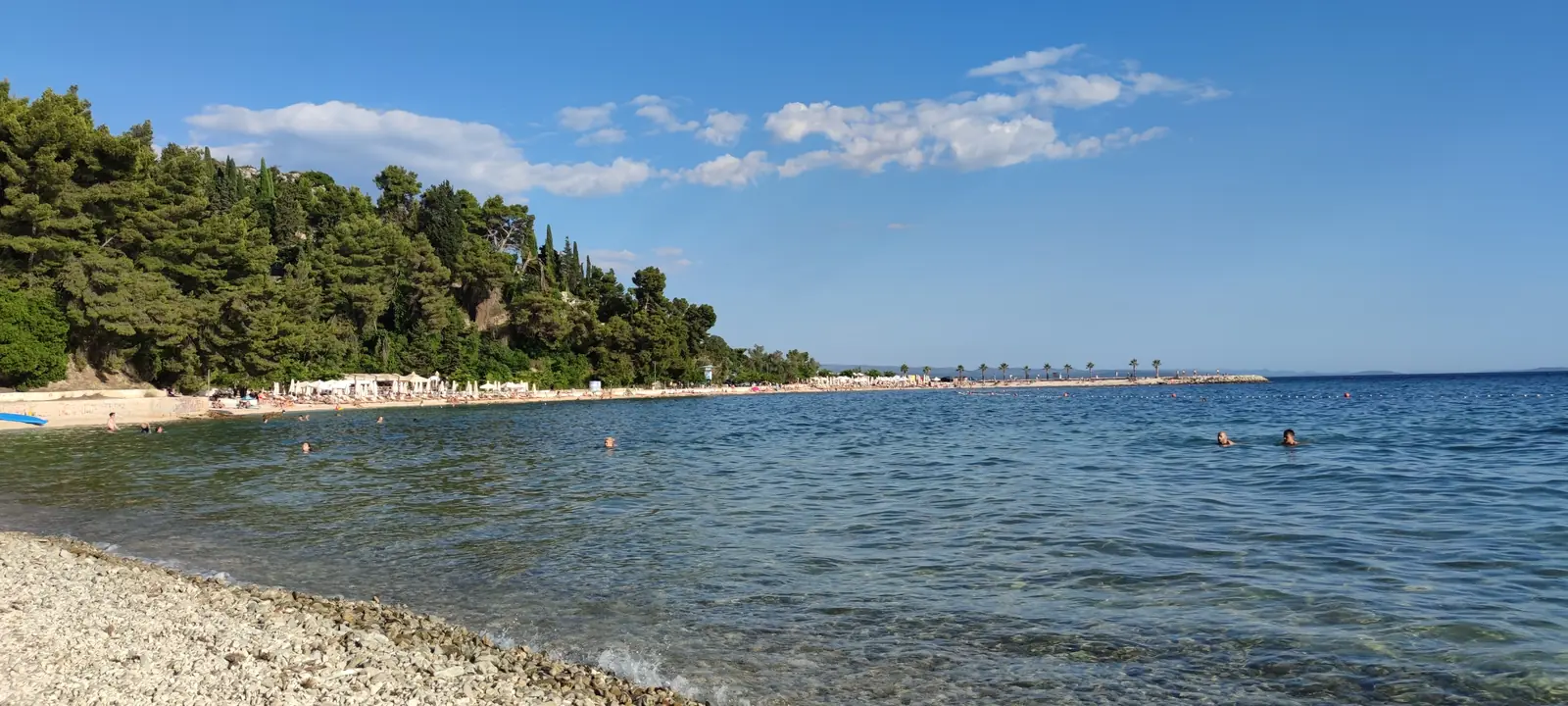 The pebble beach of Kasjuni below the pine-covered slopes of Marjan in Split, Croatia